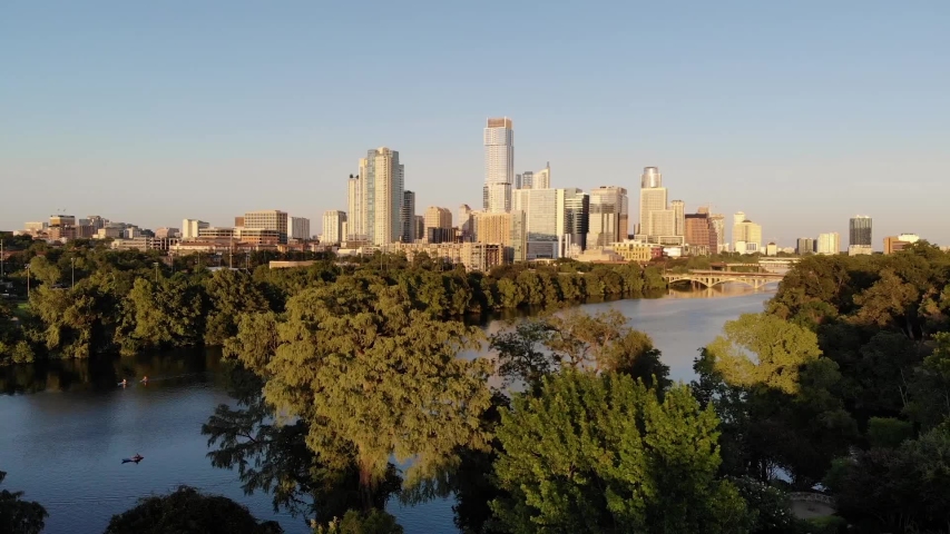 Aerial Drone shot of Downtown Austin, Texas. Shot from the Southwest, coming from Zilker park. Coming over the trees revealing town lake and the downtown skyline. Royalty-Free Stock Footage #1036057505