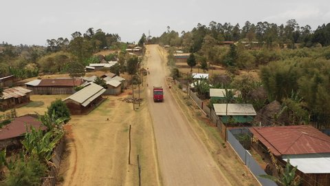 Frontal drone shot of Chinese construction truck driving over dusty mountain road through small village community of Dorze in South Ethiopia Africa

