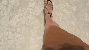 A woman in sandals and a brown dress is walking on dry cracked ground. Close view of the legs. - Powered by Shutterstock - Get 15% off with code: PIKWIZARD15