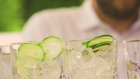Bartender preparing, pouring refreshing drink with bubbles, ice and lime, gin tonic.