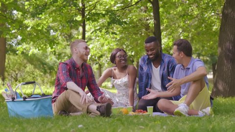 Young mixed-race people enjoying springtime together in park during picnic