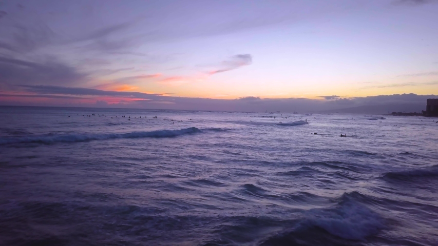 Surfers enjoy the sunset at Waikiki as they catch their final waves at dusk on the Hawaiian island of Oahu. | Shutterstock HD Video #1036079684