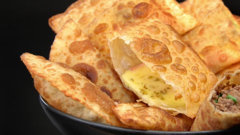 Pan in traditional pastry called pastel stuffed with cheese and meat with one each open and smoke coming out