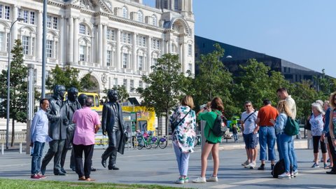 Liverpool / UK - August 26 2019:  The Beatles Statue and the queue of tourists who are taking the pictures with it. The bronze statue is a highly popular attraction in Liverpool. Time lapse video.