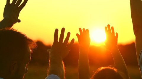 Happy big family raising hands up, Father, mother and children - little daughters together enjoying nature outdoors. Hands up in the air silhouette over sunset sky. Vacation concept. Slowmo 4K UHD