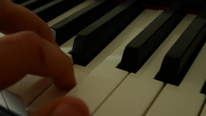 Male left hand presses piano keys. Piano playing. Musical theme. Close up of man hands playing the piano in slow motion. Music lesson. Studing music