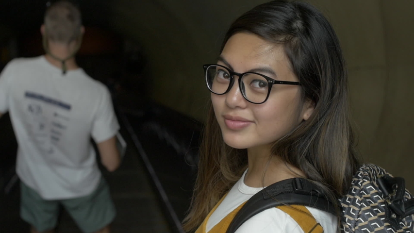 Woman Rides Escalator into Subway System