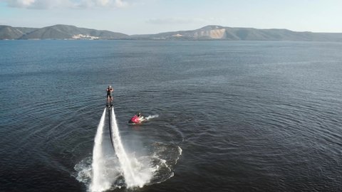 Energetic man flying on jet pack over water Stockvideo