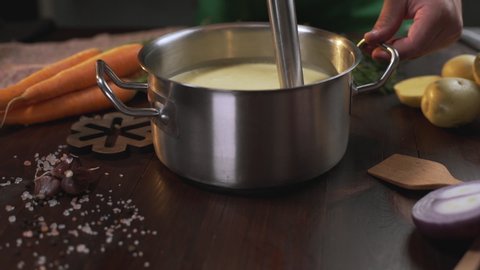 The cook uses hand blender to make mashed soup in the metal pan, cooking healthy food, mashed vegetables, Full HD Prores 422 HQ