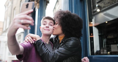 Young adult lesbian couple taking selfie in London