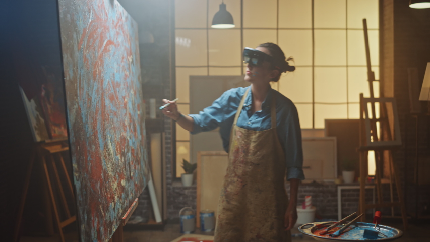 Talented Female Artist Wearing Augmented Reality Headset Working on Abstract Painting, Uses Paint Brush To Create New Concept Art Using Virtual Reality Interface. High tech Creative Modern Studio Royalty-Free Stock Footage #1036107635