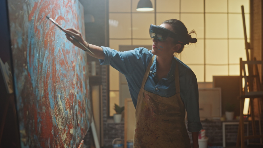 Talented Female Artist Wearing Augmented Reality Headset Working on Abstract Painting, Uses Paint Brush To Create New Concept Art Using Virtual Reality Interface. High tech Creative Modern Studio | Shutterstock HD Video #1036107635
