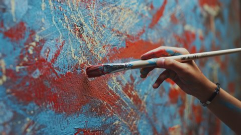 Close-up Shot of Female Artist Hand, Holding Paint Brush and Drawing Painting with Red Paint. Colorful, Emotional Oil Painting. Contemporary Painter Creating Modern Abstract Piece of Fine Art