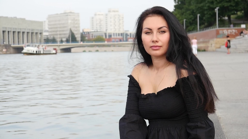 An elegant Woman Brunette posing looking Face to a Camera Portrait on a City Street River Bank - Wroclaw, Poland