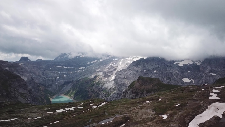 Distant aerial view of the Limmernsee reservoir and dam near Linthal(Switzerland). In the main focus are the alpine mountins and peaks which sorround the valley of the lake. Shot taken on a cloudy day