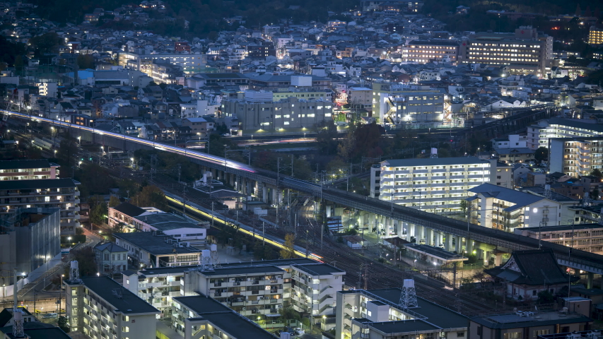 KYOTO, JAPAN, Bullet trains and commuter trains converging at twilight, heading towards Train station. Tourism and Transportation Timelapse. Royalty-Free Stock Footage #1036112405