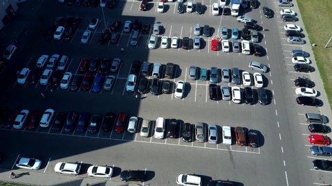 A view from above to the process of car parking. Heavy traffic in the parking lot. Searching for spaces in the busy car park. Parking advice. Cruising for parking in busy business center