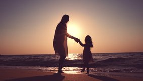 Happy family and sea sunrise. Mother and little girl dancing on the beach.
