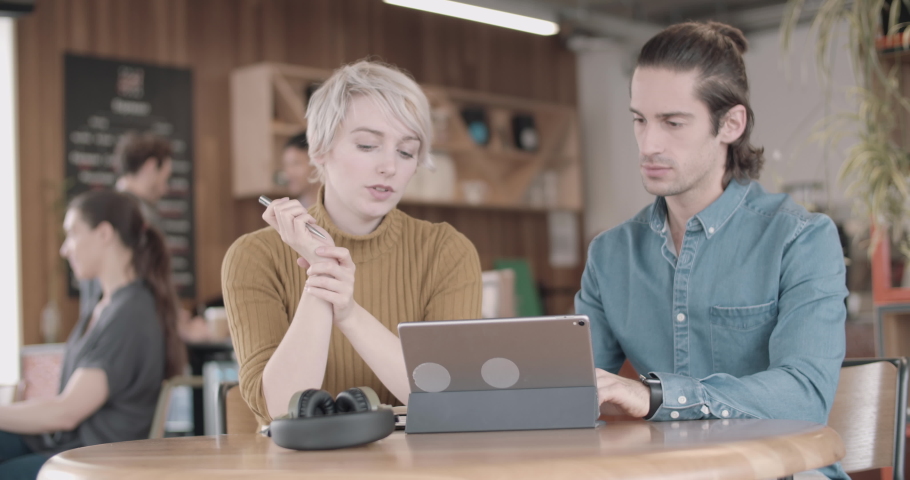 Freelancers in a meeting at a cafe looking at a digital tablet