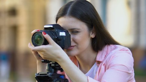 Pretty smiling female photographer calibrating camera lens mass media profession