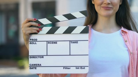 Young woman holding clapperboard, assistant film director, video production