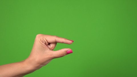 Closeup view of female one hand showing different sizes of invisible virtual objects by her fingers from very small to very big. Hand isolated on green background. Real time 4k video footage.