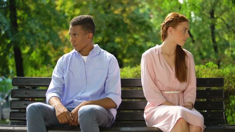 Two offended teenagers sitting on bench separately, quarrel