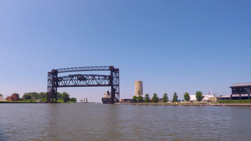 Boats, kayaks, jet skis all coast by in a day time-lapse on the Cuyahoga River in Cleveland Ohio. The Flats entertainment district shows life on the river and recreation mixed with shipping industry.