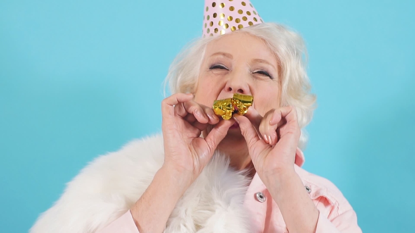 Cheerful pleasant pretty old lady holding party horns and looking at camera, entertainment. Royalty-Free Stock Footage #1036143764