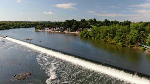 Descending aerial drone dolly shot toward Fairmount Park above Schuylkill River waterfall on beautiful summer day