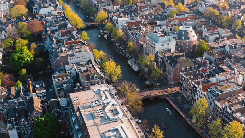 Amsterdam, Netherlands: sunny drone view of bridge above narrow canal with traffic of tourist boats