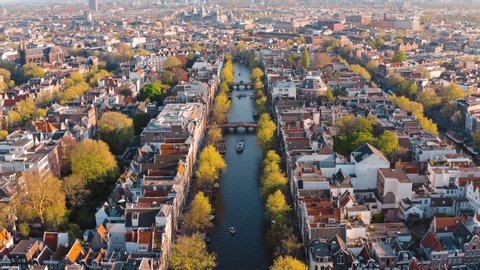 Amsterdam, Netherlands: drone flight along narrow canal with boats in the center city