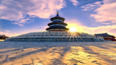 Sunrise at the Temple of Heaven, Beijing, China with a dramatic sky with clouds and the sun with sun beams appearing over a way