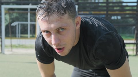 Exhausted man raises head and looks into camera. Close-up tired face and sweaty man finished workout outdoors.