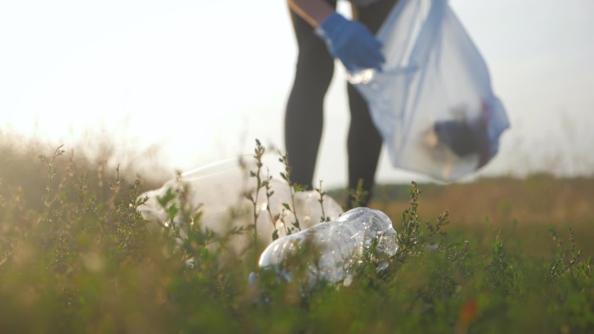 Care about nature. Volunteer girl collects trash in the trash bag. Trash-free planet concept. Nature cleaning, volunteer ecology green concept. Environment plastic pollution. | Shutterstock HD Video #1036162082