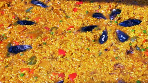 Seafood Paella boiling in a large hot pan.