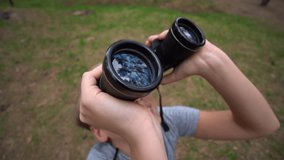 White handsome kid exploring nature outdoor using old black binocular. Slow motion full hd video footage.