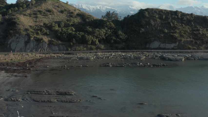 Kaikoura seaside aerial rise reveal of snow capped mountains in New Zealand