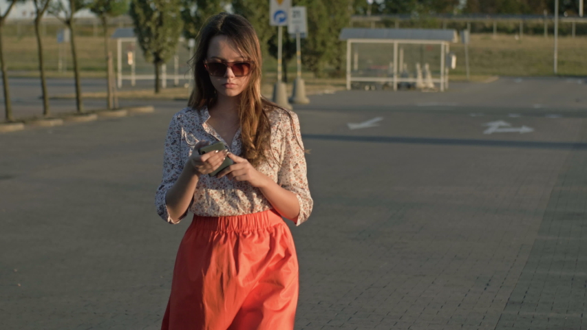 Beautiful caucasian girl walking down the street looking at her cell phone was almost hit by a car. Concept - smartphone addiction. Royalty-Free Stock Footage #1036174013
