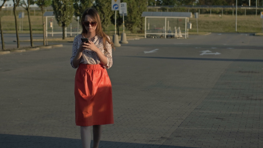 Beautiful caucasian girl walking down the street looking at her cell phone was almost hit by a car. Concept - smartphone addiction. Royalty-Free Stock Footage #1036174019
