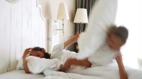 Funny video about annoying little daughter comes in bedroom to sleeping father, climbs on him and starts to jump for wakes him. Father wakes up, hits child by pillow and she falling on the bed.