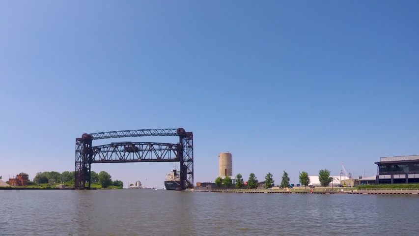 Boats, kayaks, jet skis all coast by in a day time-lapse on the Cuyahoga River in Cleveland Ohio. The Flats entertainment district shows life on the river and recreation mixed with shipping industry.