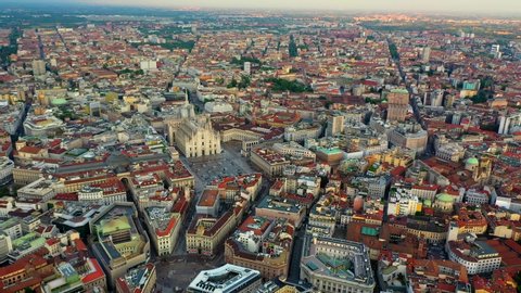 Duomo di Milano Cathedral, Aerial, reverse, drone shot, panning towards the church over buildings and architecture in the cityscape of Milan city, on a sunny evening, in Lombardy, Italy