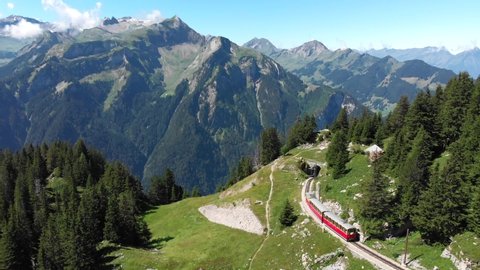 Aerial Tracking Shot of Swiss Cogwheel Train Going into Mountain Tunnel.
