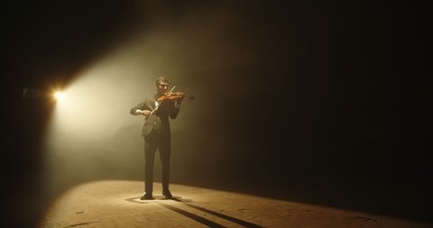 Asian violinist performing on stage. Popular musician playing solo on his his instrument on smoked black background 4k footage