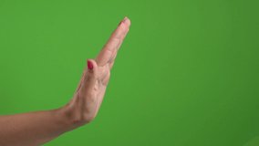 Closeup side view of woman making stop gesture. One female hand isolated on green background. Real time 4k video footage.