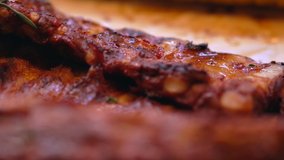 Selective focus panning shot over grilled meat with crispy brown skin in a low angle view at a barbecue