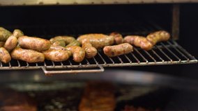 Pork sausages grilling on an electric grill with a rotating base with portions of beef ribs at a fast food outlet at a catered event