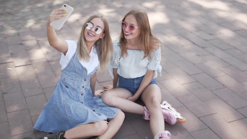 Girls in rollerblades taking a selfie while sitting down
