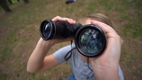Closeup view of cute caucasian kid holding old black binocular in hands and looking at something inteersting in distance. Slow motion full hd video footage.